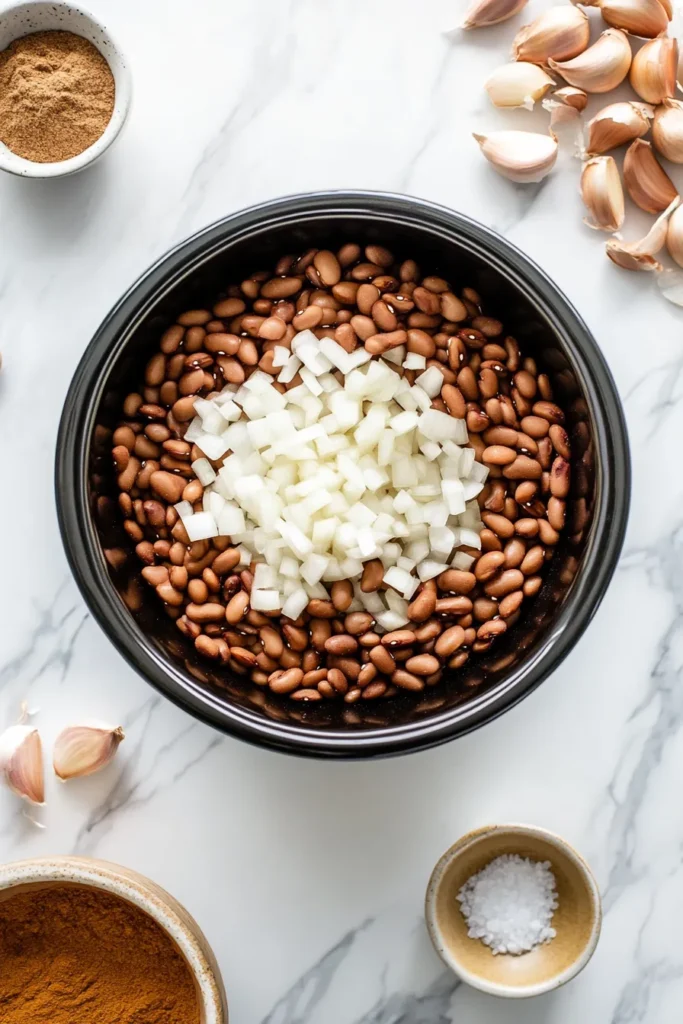 Ingredients for pinto bean crock pot recipe laid out on a clean kitchen counter in a daylight urban apartment.